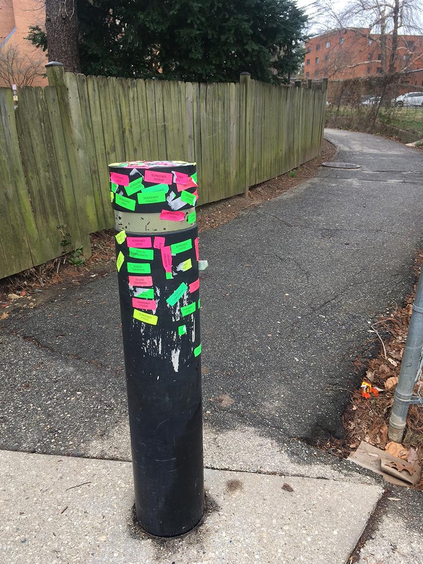 A pole on the street near the National Library of Medicine is covered in colorful Clinical Center check-in stickers 