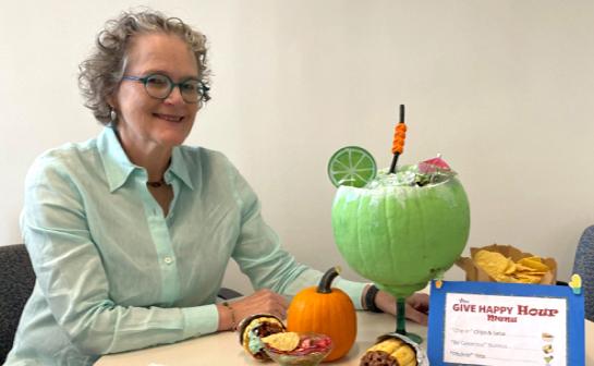 Marrazzo seated at table with large green pumpkin carved in the shape of a margarita glass, with lime and straw