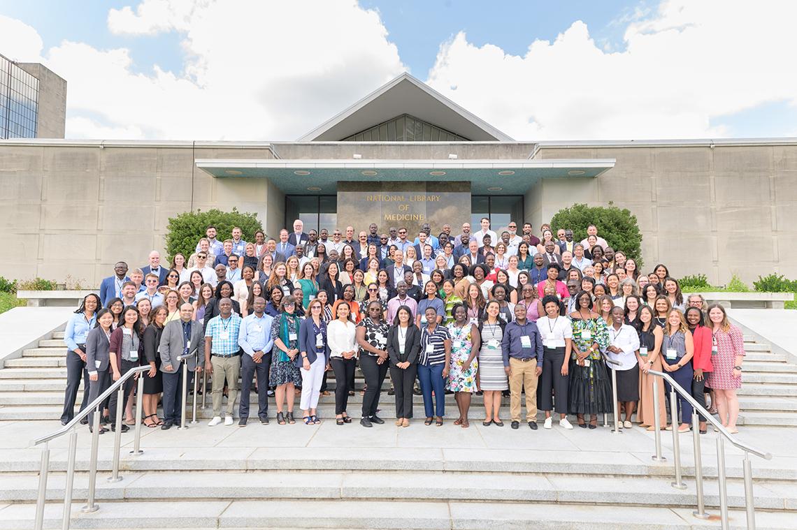 Large group of staff and trainees pose outside on concrete steps