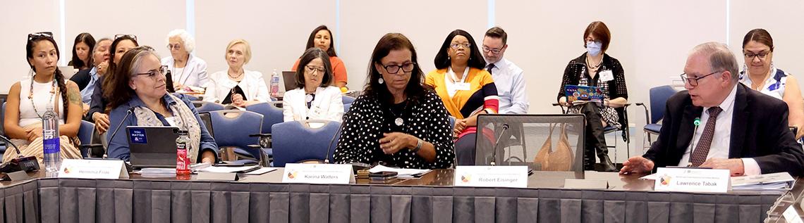Frias, Walters and Tabak sit at a long conference table with other participants seated behind.