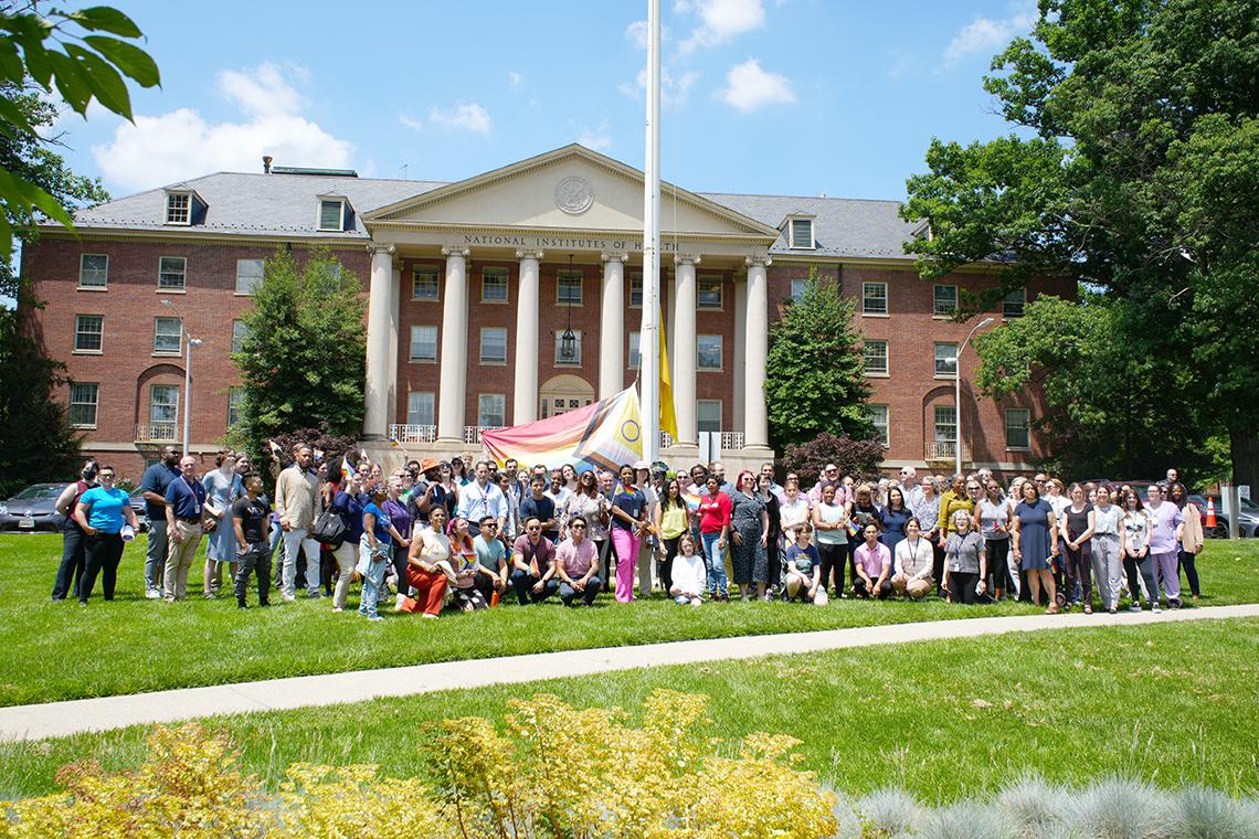 A group photo of attendees and the Pride flag
