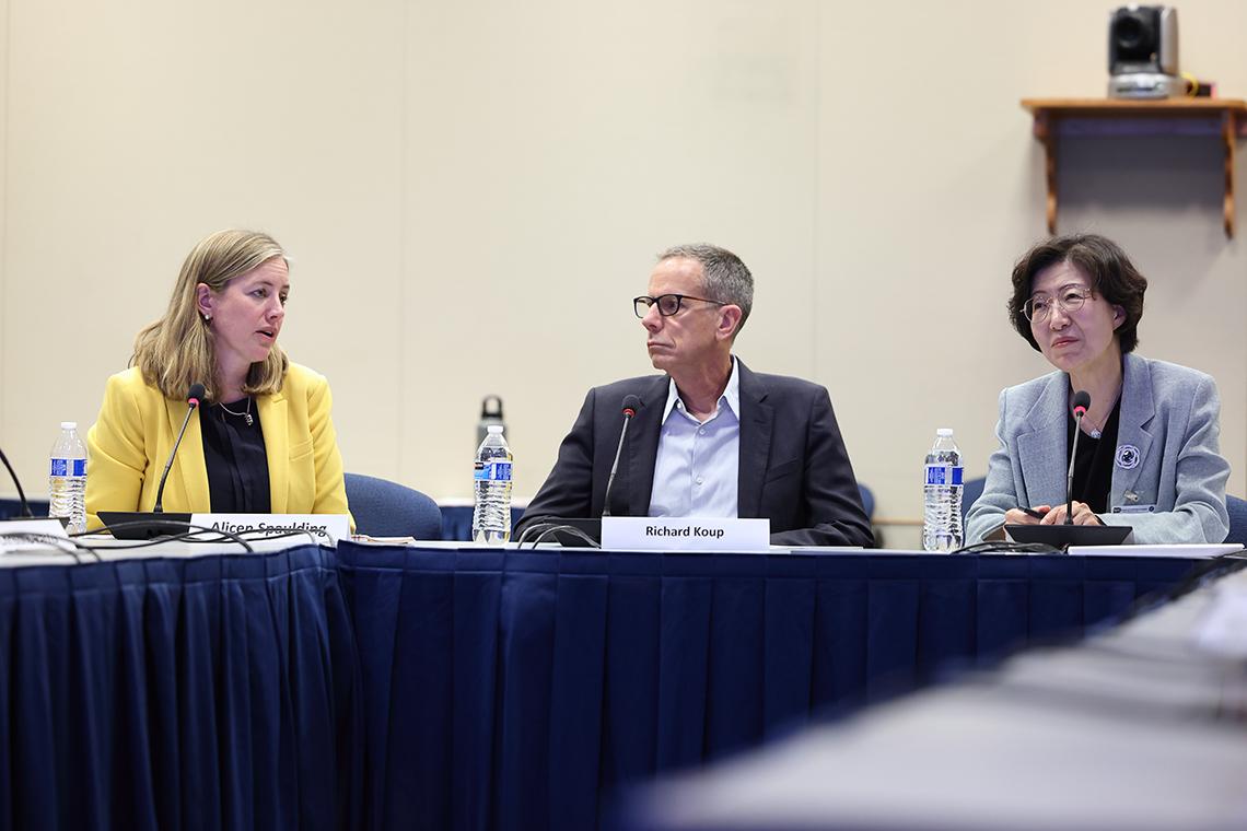Park and two of the meeting's NIH participants, seated at a long table.