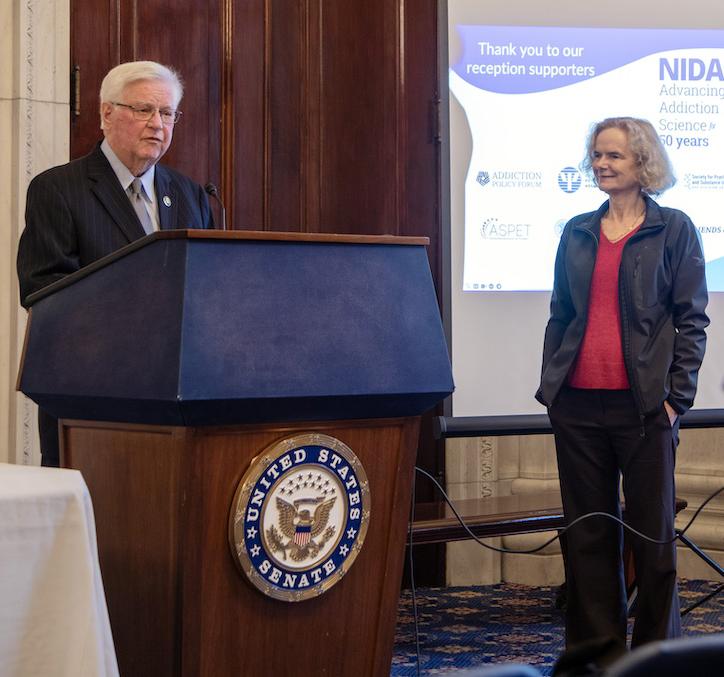 Congressman Rogers at podium as Volkow stands nearby