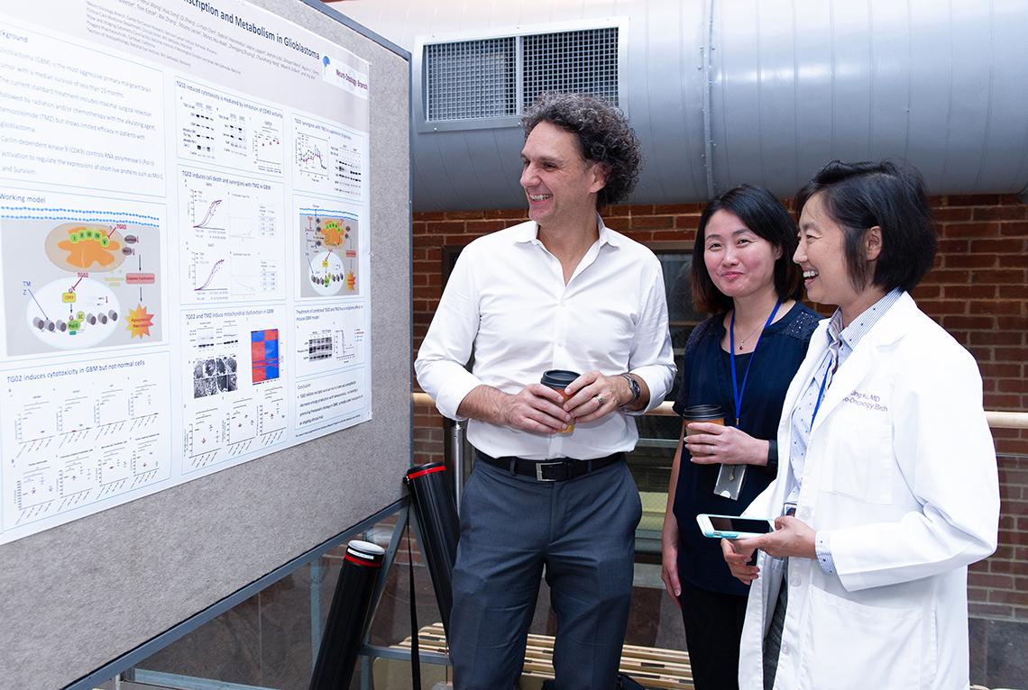 Three people look at a poster