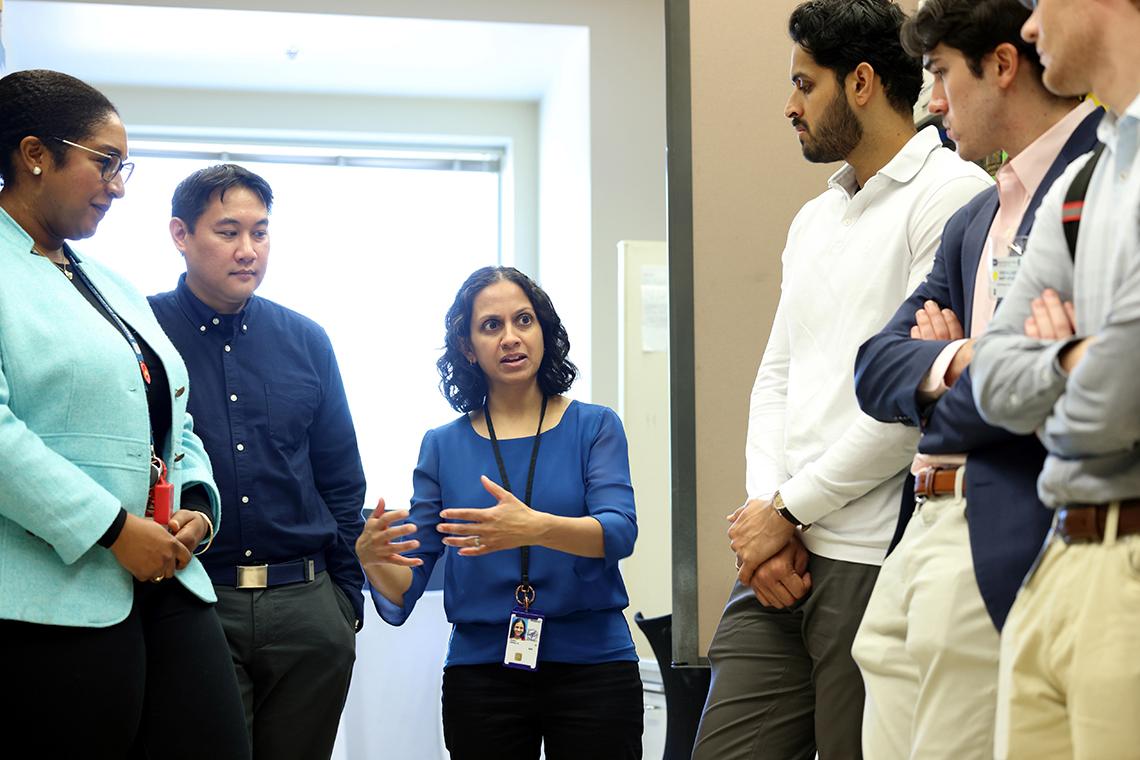 Several people gathered around a woman speaking in a corridor.