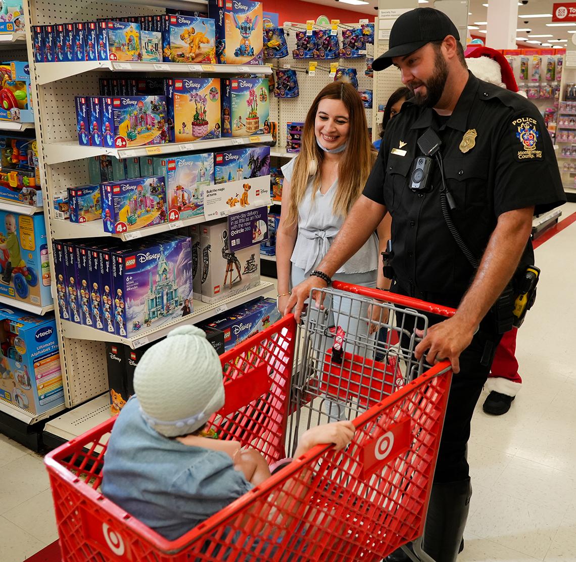 An officer pushes a cart with child riding inside in the store.