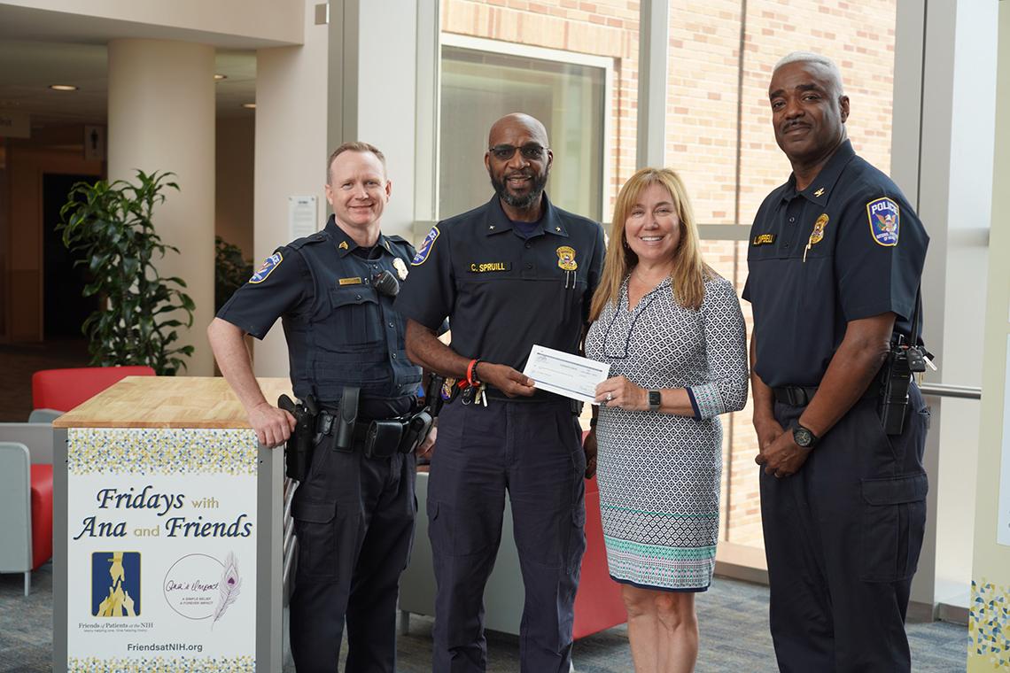 Three uniformed NIH Police officers present a check to Williams.