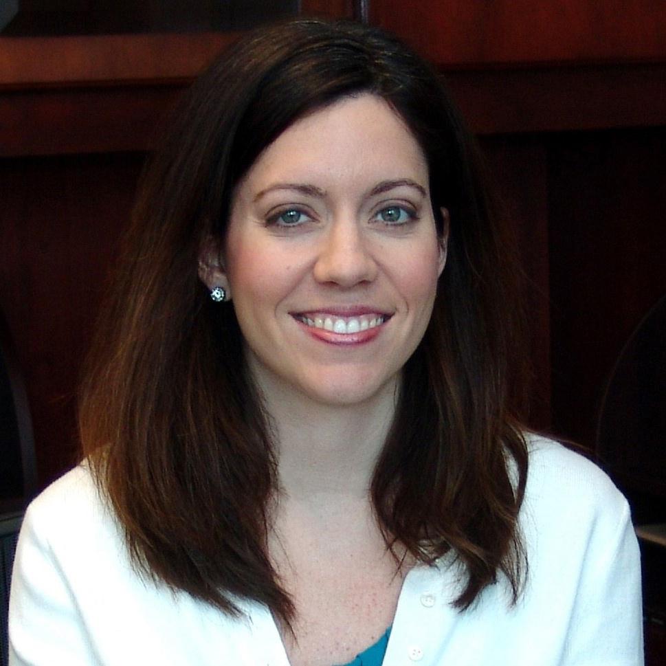 Headshot of Kitahara, who wears a white coat and poses against a dark backdrop.