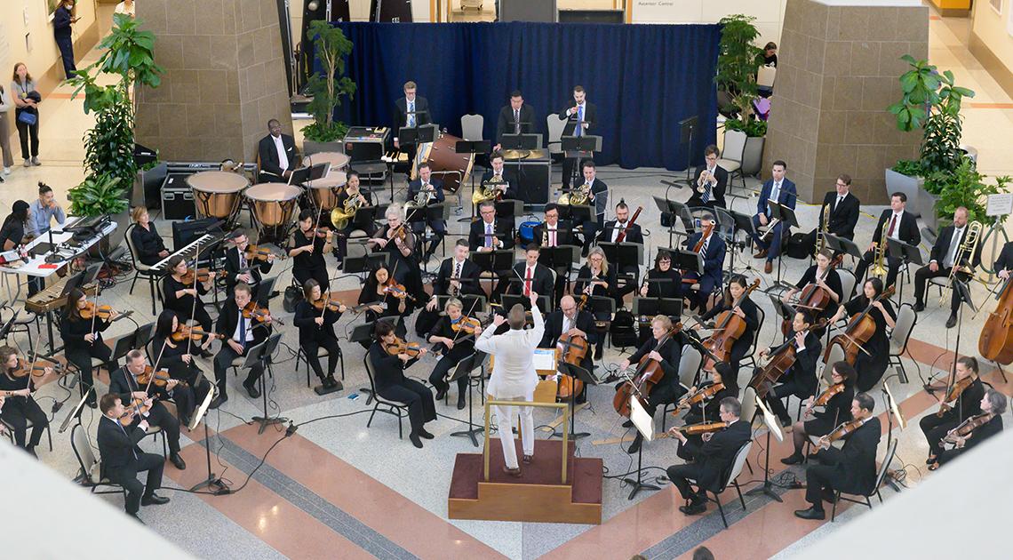 Full orchestra, seen from above, performs in the CC atrium.