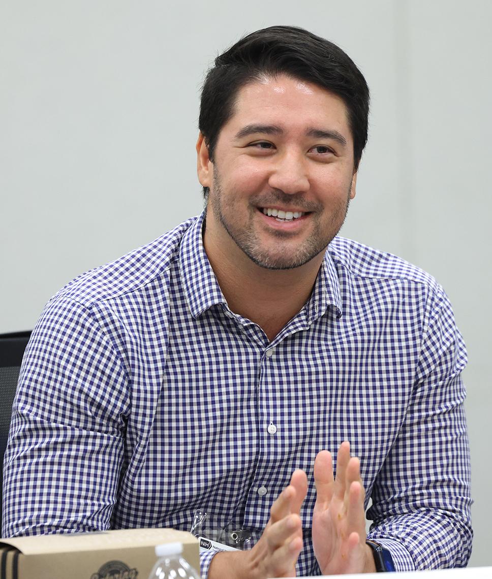 A seated man smiling, talking