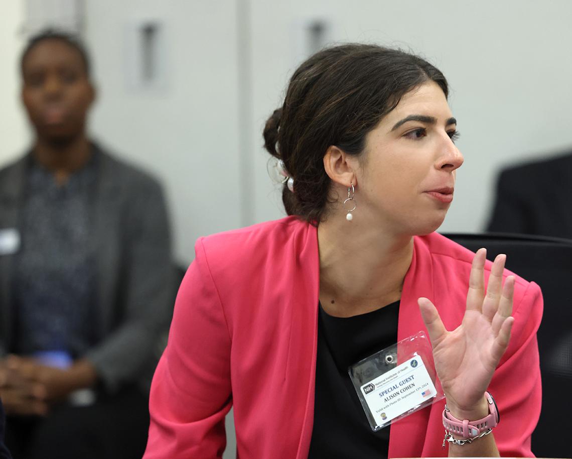A woman in pink sweater talks, profile view
