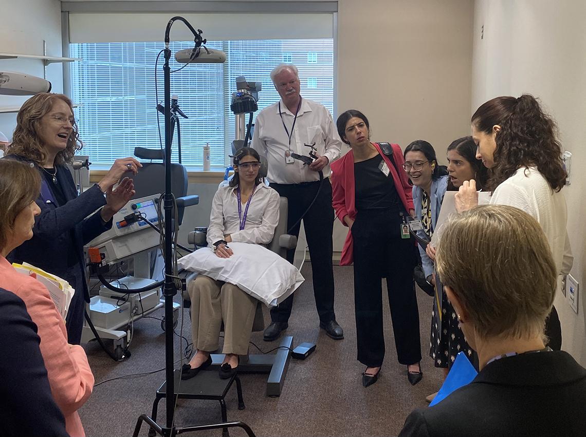 Woman in chair with medical equipment, surrounded by people in lab