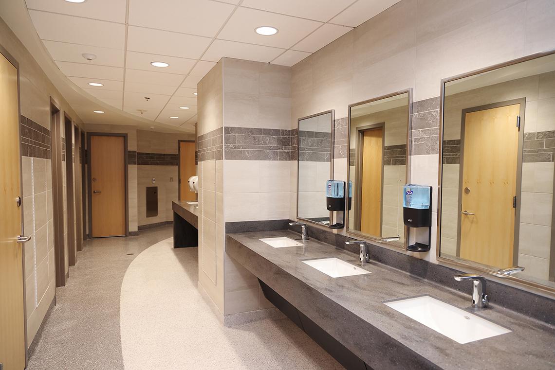 New bathroom - sinks, mirrors on one side and stalls with tall doors on the other