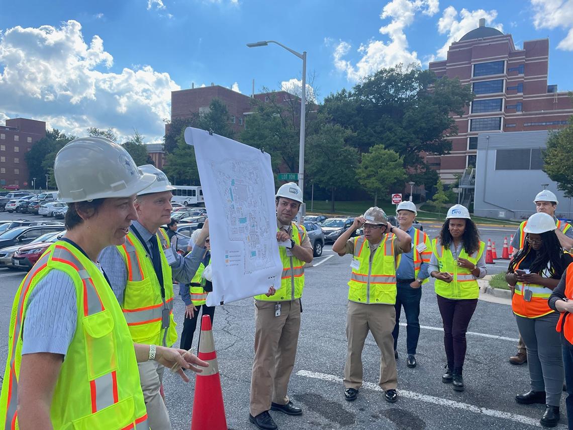 Roberts speaks in a parking lot while her colleagues hold up poster board.