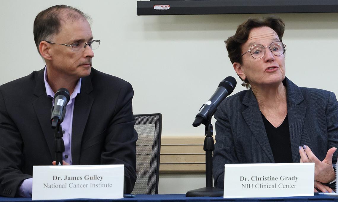 Seated at conference table, Grady (right) talks as Gulley looks on.