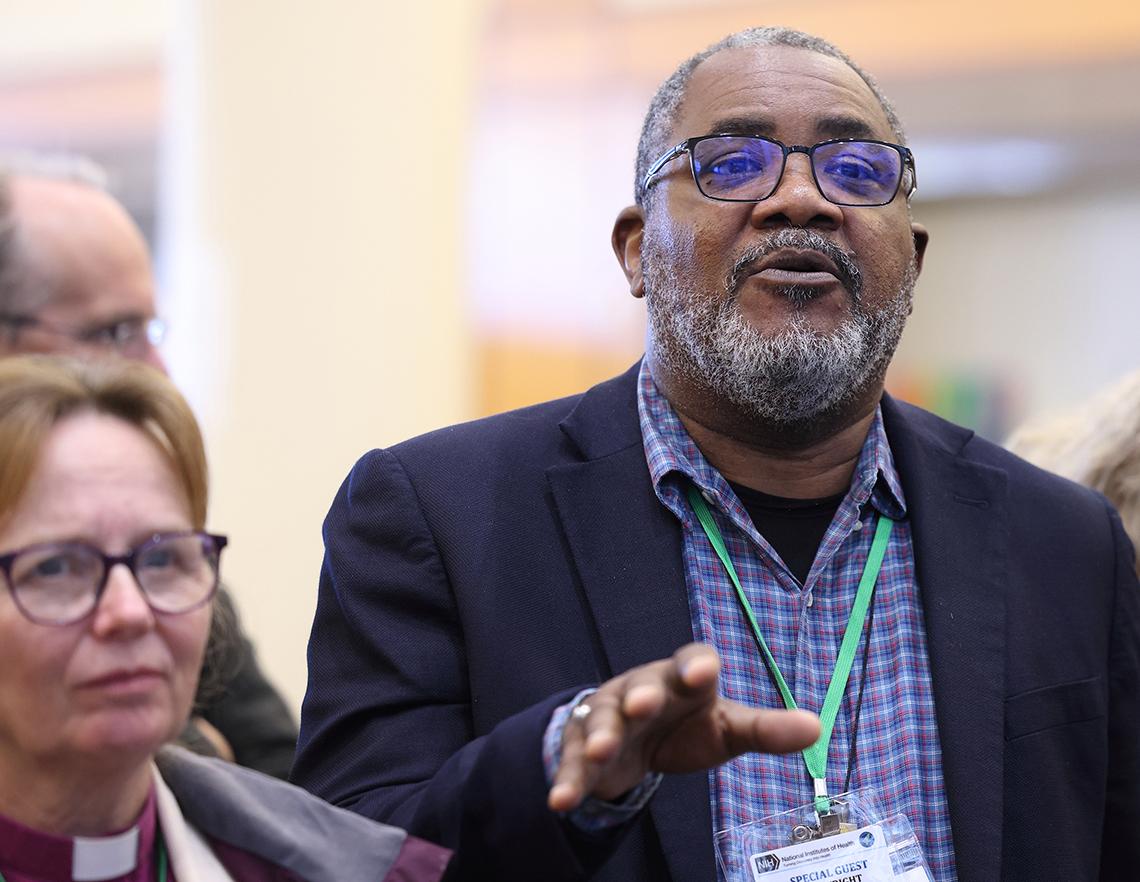 Rev. Wright with palm outstretched talks in Clinical Center atrium.