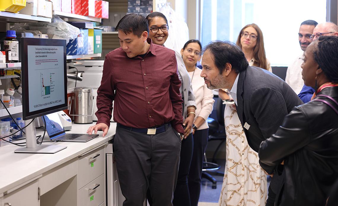 A man bends down to peer at a screen in a Clinical Center laboratory.