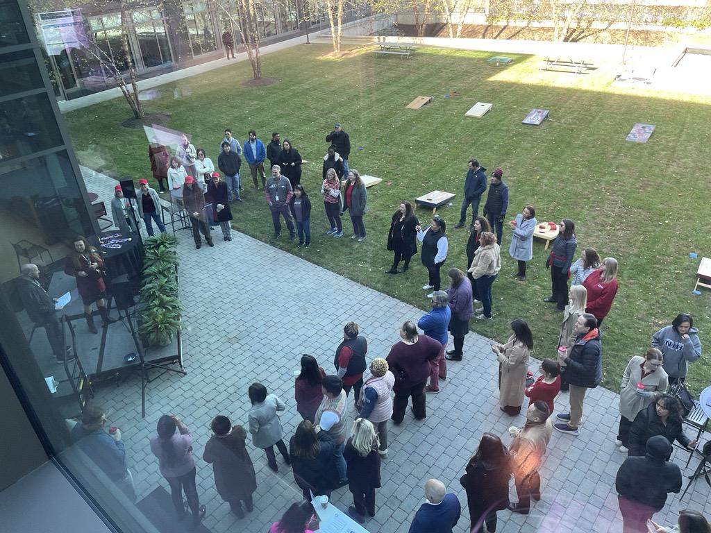 Overhead shot of people gathered outside NCI-Shady Grove with cornhole boards set up on the lawn