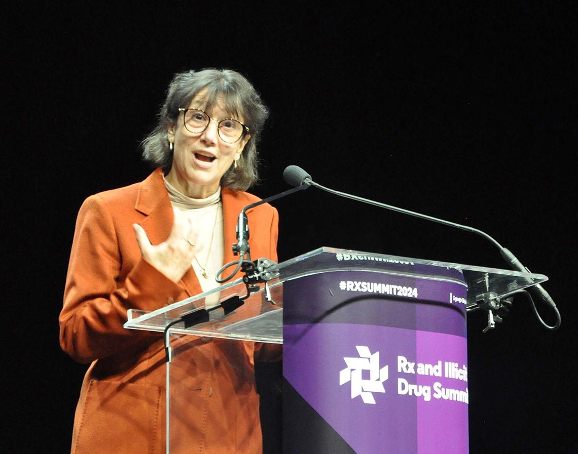 Bertagnolli speaks earnestly at a lectern bearing the Rx and Illicit Drug Summit banner