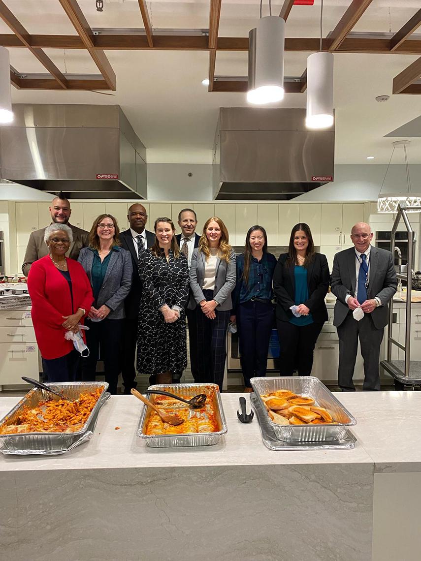 The servers stand proudly behind half-empty platters of food.