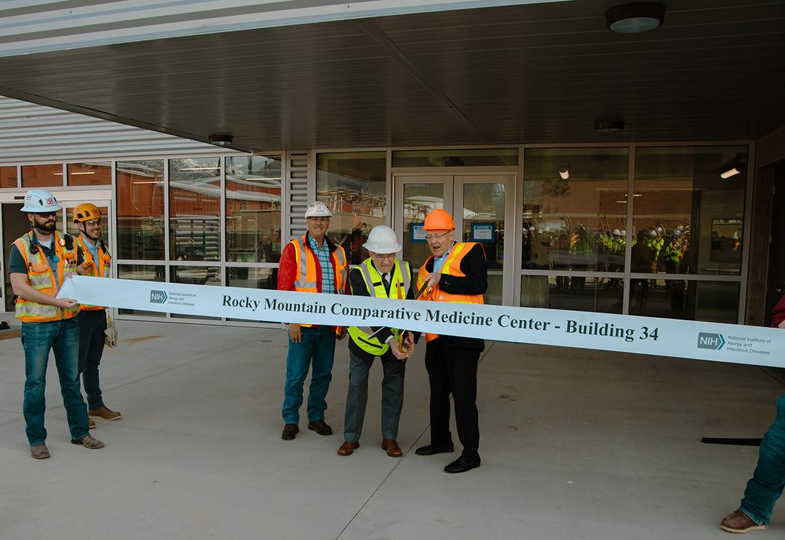 Outside the building, a man holds big scissors to ribbon that reads: Rocky Mountain Comparative Medicine Center - Building 34