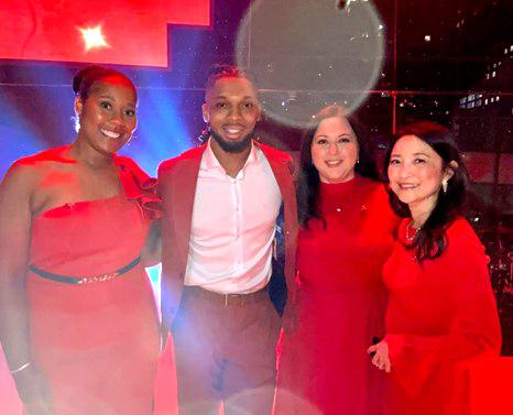 Three NIH'ers smile for a photo with NFL player Damar Hamlin. All wear red outifts.