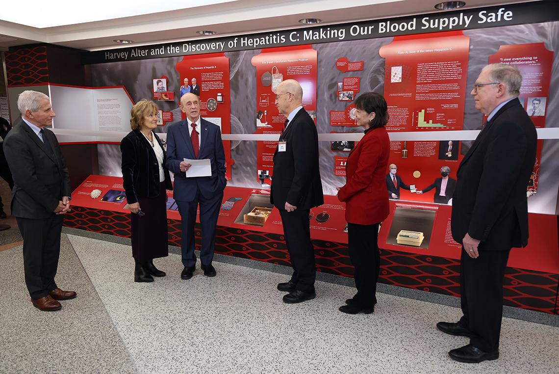 Alter reads off a paper while leadership looks on