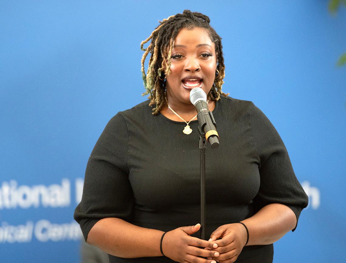 Black woman sings into microphone.