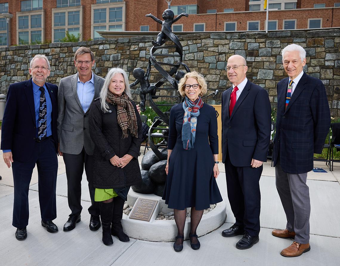 Six individuals pose for a photo in front of the statue.