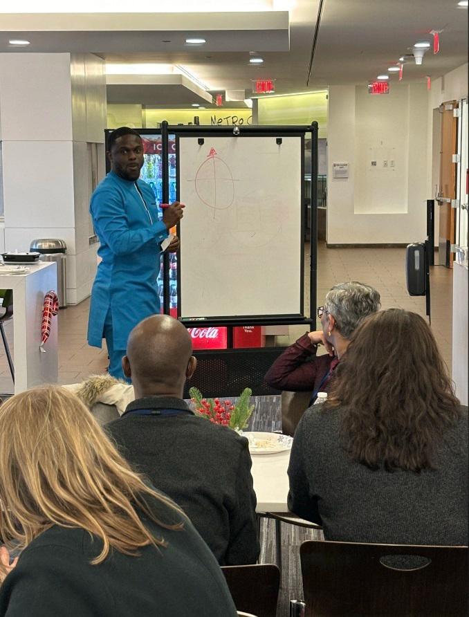 A man in blue lectures at a whiteboard.
