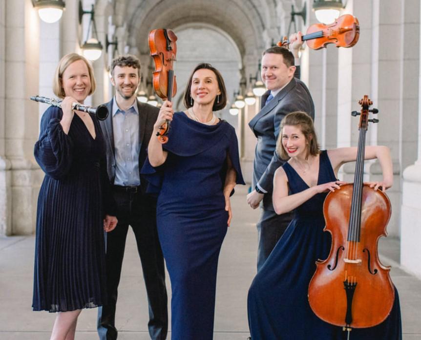 Five musicians of Kassia pose together with instruments, under an archway