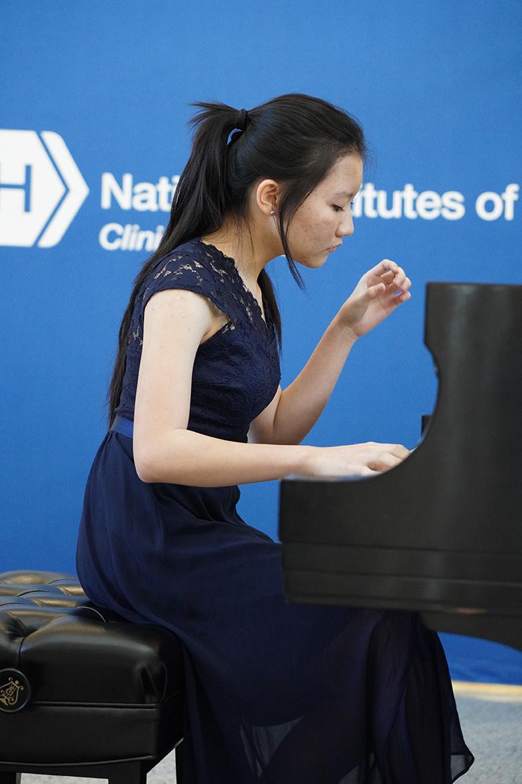 Zhong with one hand on piano keys in CC atrium
