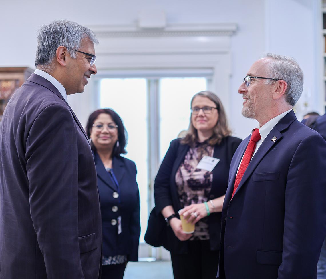 Bhattacharya converses with 3 people at Stone House on NIH campus