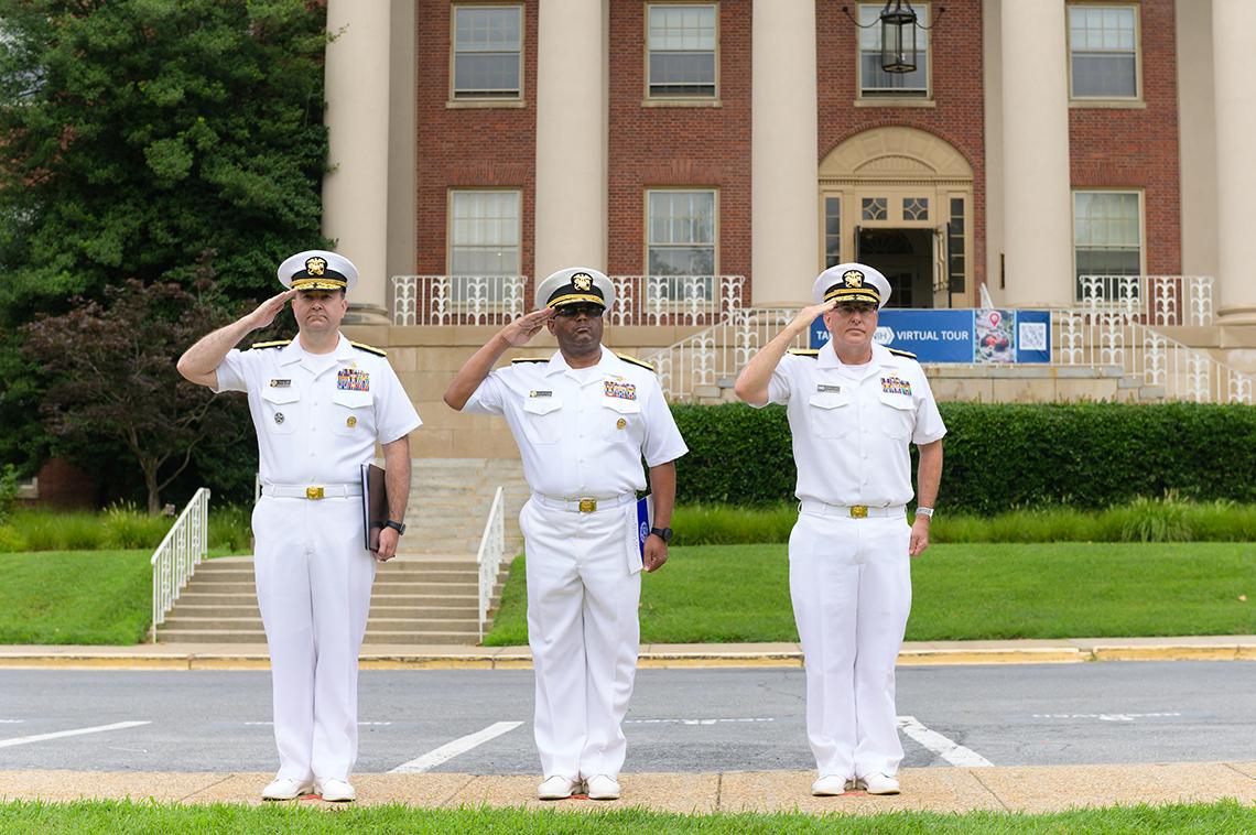 Three PHS officers salute in front of Bldg. 1