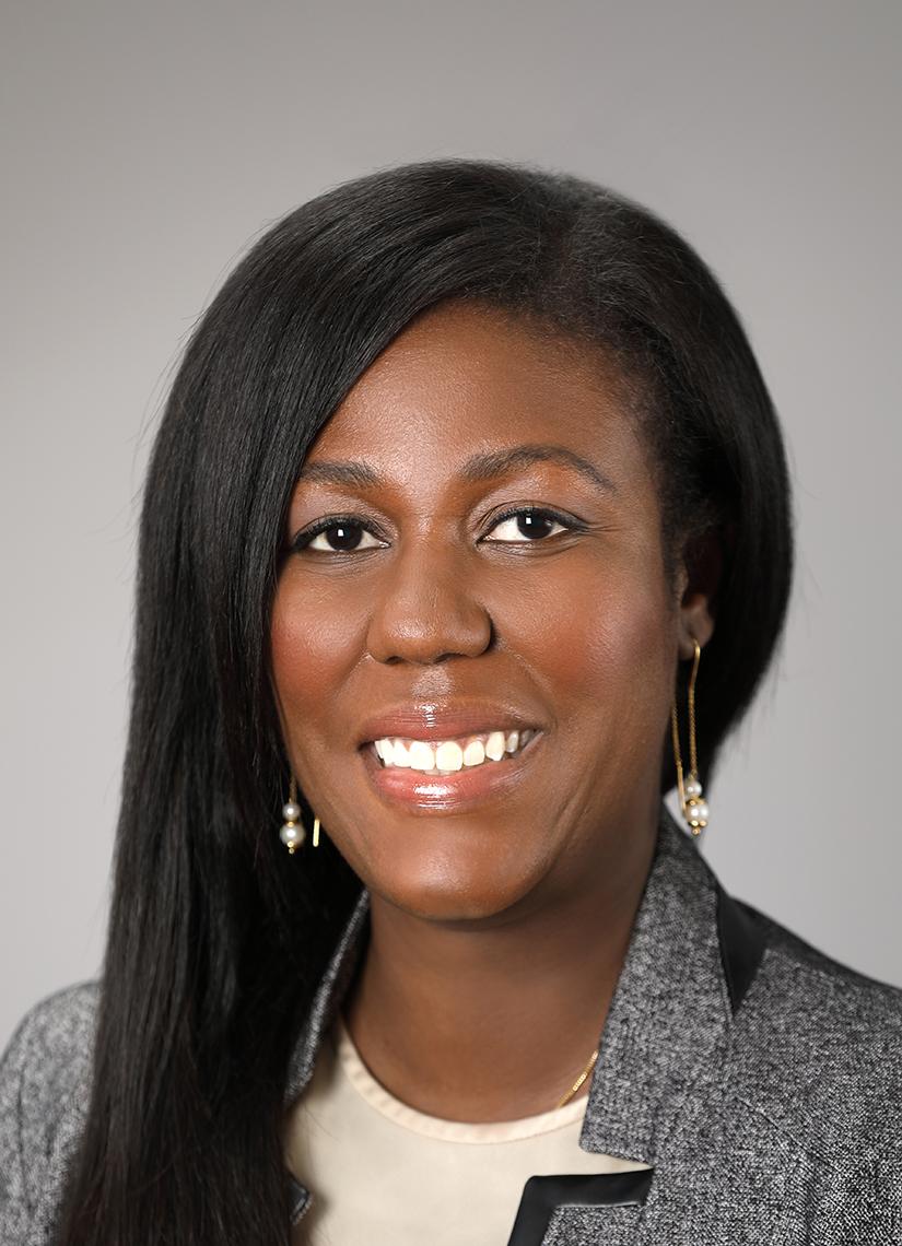 Headshot of Dr. Joseph against a light gray background. She is wearing a gray jacket and long earrings.