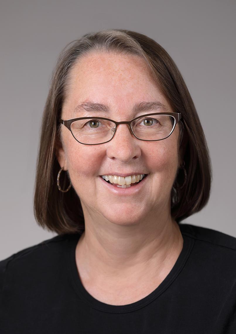 Headshot of a smiling Storz, who wears glasses and is framed by a light gray background