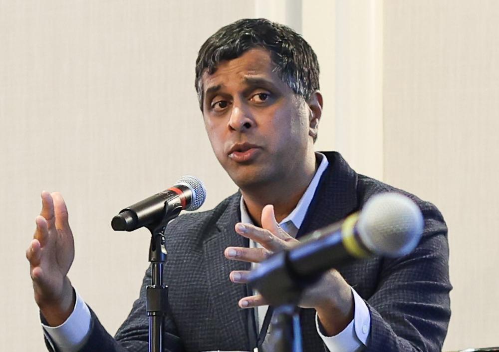 Gopal talks into mic with palms extended 