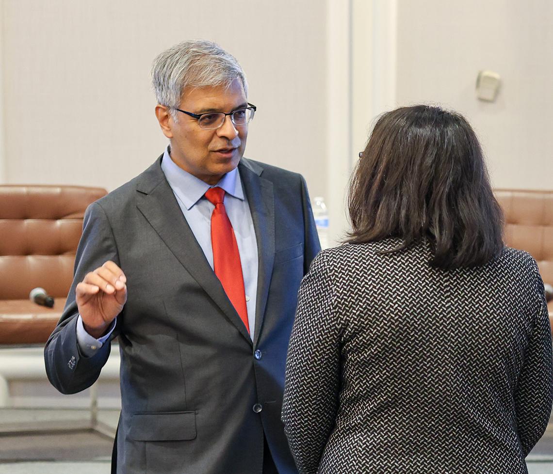 Bhattacharya with hand curled talks with woman (seen from behind)