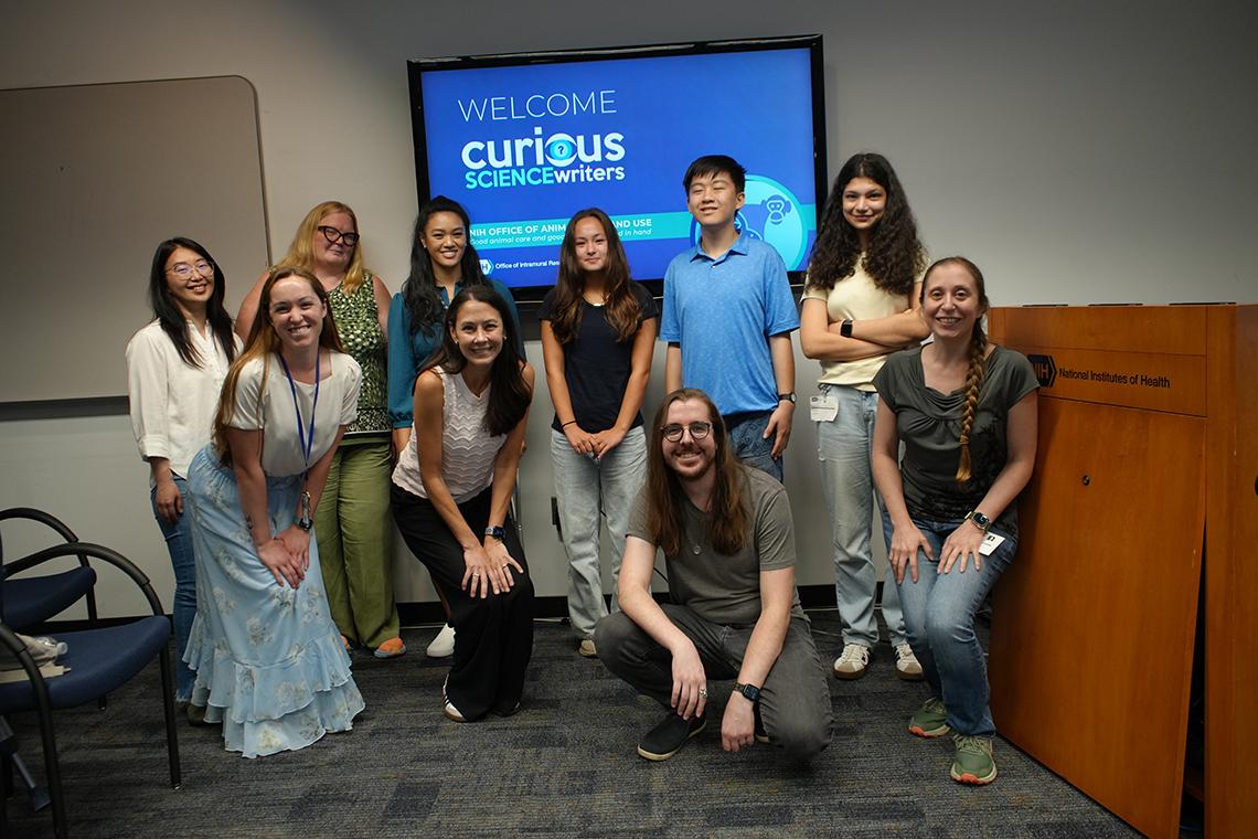The group of presenters, mentors and students pose for a photo in front of a projector screen featuring the cSw logo