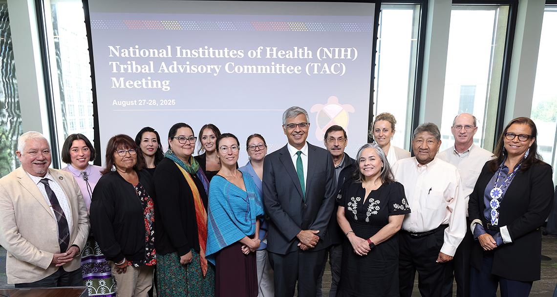 Bhattacharya and group pose together in front of Tribal Advisory Committee meeting slide.