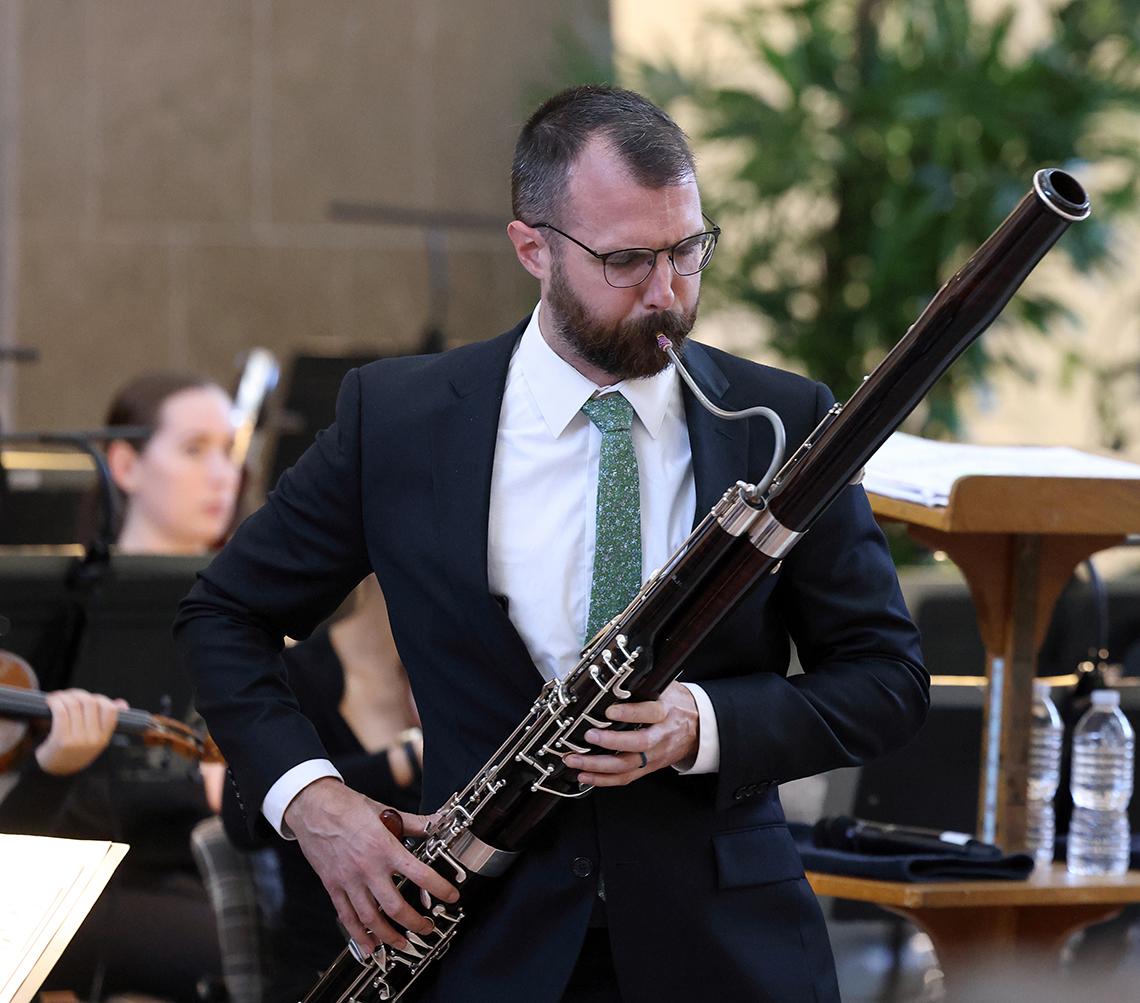 A man stands playing bassoon.