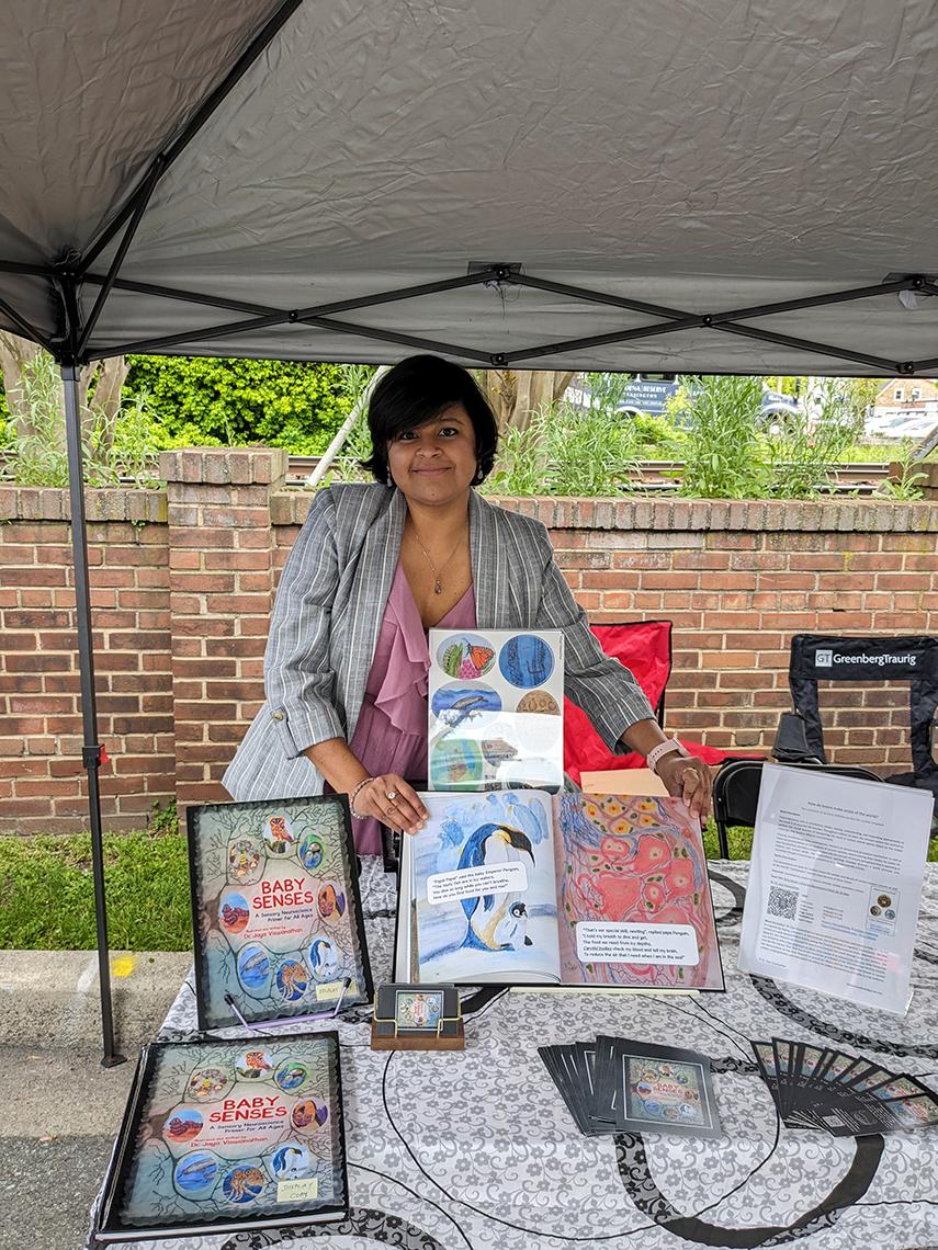 Viswanathan displays her neuro-art at a table under a tent.
