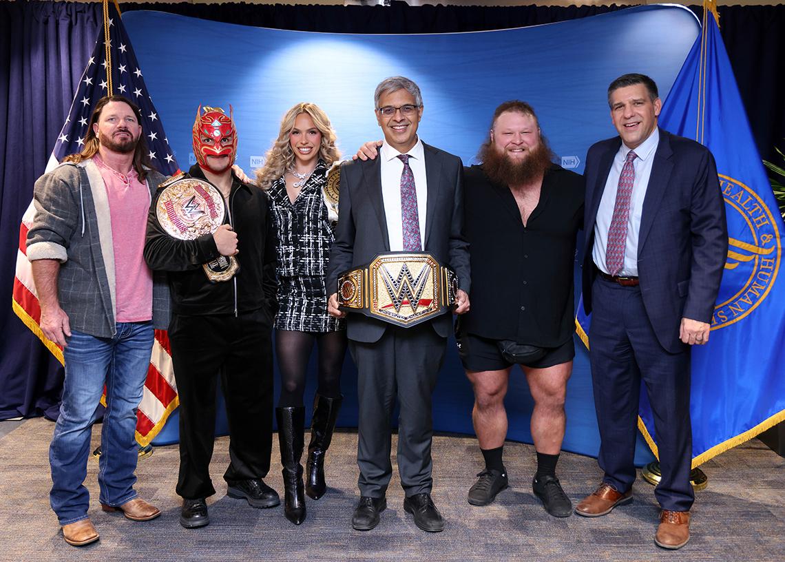 Bhattacharya and Memoli pose with the four wrestlers and a title belt.