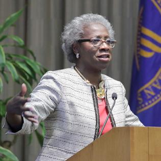 Valantine speaks at podium.