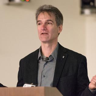 Dr. Kenneth Catania holds hands out wide, speaking at podium