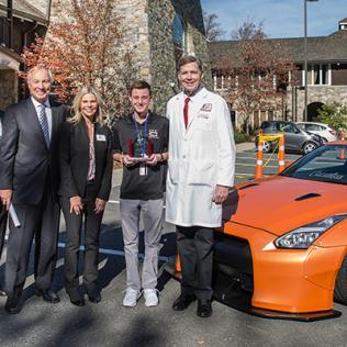 Andrew Lee and family greet Dr. Linehan in front of sports car.