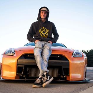 Andrew Lee poses in front of his bright orange Nissan GTR