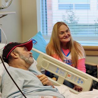 Lying in a hospital bed, Garces-Soto, with his wife Lyssette seated beside him, chats with Dr. Apolo.
