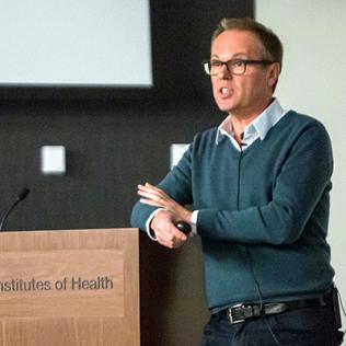 Dr. Gero Miesenböck lectures at a podium.