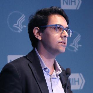 Dr. Neville Sanjana speaking at the podium.